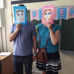 Rodzice uczniów pozują do zdjęcia ze swoimi portretami