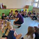 Uczniowie siedząc w okręgu oglądają prezentację robota.