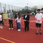 Przedstawiciele miasta i uczniowie szkoły przecinają wstęgę.