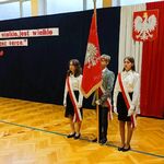 Uczniowie z pocztu sztandarowego stają na baczność. Prezentują flagę.