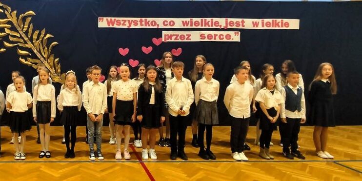 Uczniowie stoją przed publicznością. Prezentują przygotowany montaż poetycko-muzyczny.