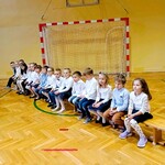 Uczniowie przedszkola siedzą na ławce. Czekają na swoją kolej wystąpienia.