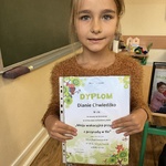 Uczennica pozuje do zdjęcia. Prezentuje swój dyplom.