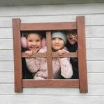 Troje dzieci w okienku drewnianego domku.