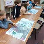 Uczniowie biorą udział w zajęciach. Układają duże puzzle banknotów