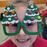 Uczennica pozuje do zdjęcia w świątecznych okularach.