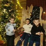 Chłopcy siedzą na krześle Świętego Mikołaja.