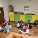 Uczniowie pracują w grupach. Siedzą na podłodze.