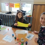 Uczniowie wykonują zadania z języka polskiego. Uczennica maluje farbą wyrazy na kartce.
