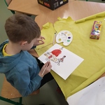 Uczeń maluje farbami. Siedzi przy ławce