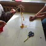 Uczniowie pracują w grupach. Budują wieżę z makaronu, sznurka i taśmy.