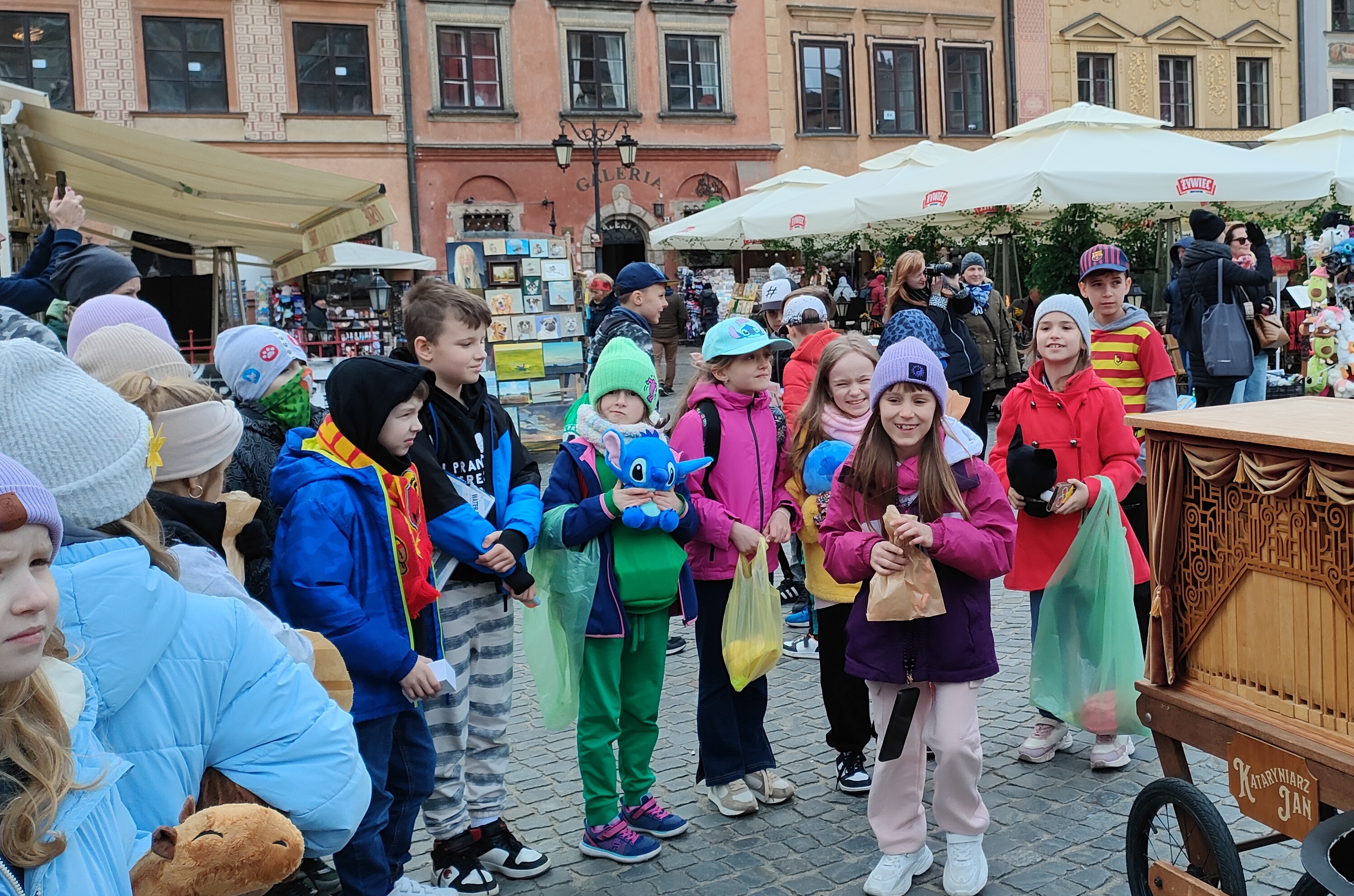 Uczniowie stoją w półkolu. Słuchają występu kataryniarza..jpg