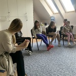 Uczniowie podczas warsztatów. Siedzą na krzesłach w kole