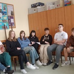 Uczniowie podczas zajęć. Siedzą na krzesłach w kole