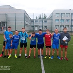 Uczniowie pozują do zdjęcia na boisku szkolnym. Są ubrani w stroje sportowe