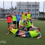 Uczniowie pozują do zdjęcia na boisku szkolnym. Są ubrani w stroje sportowe