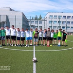 Uczniowie pozują do zdjęcia na boisku szkolnym. Są ubrani w stroje sportowe