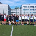 Uczniowie pozują do zdjęcia na boisku szkolnym. Są ubrani w stroje sportowe