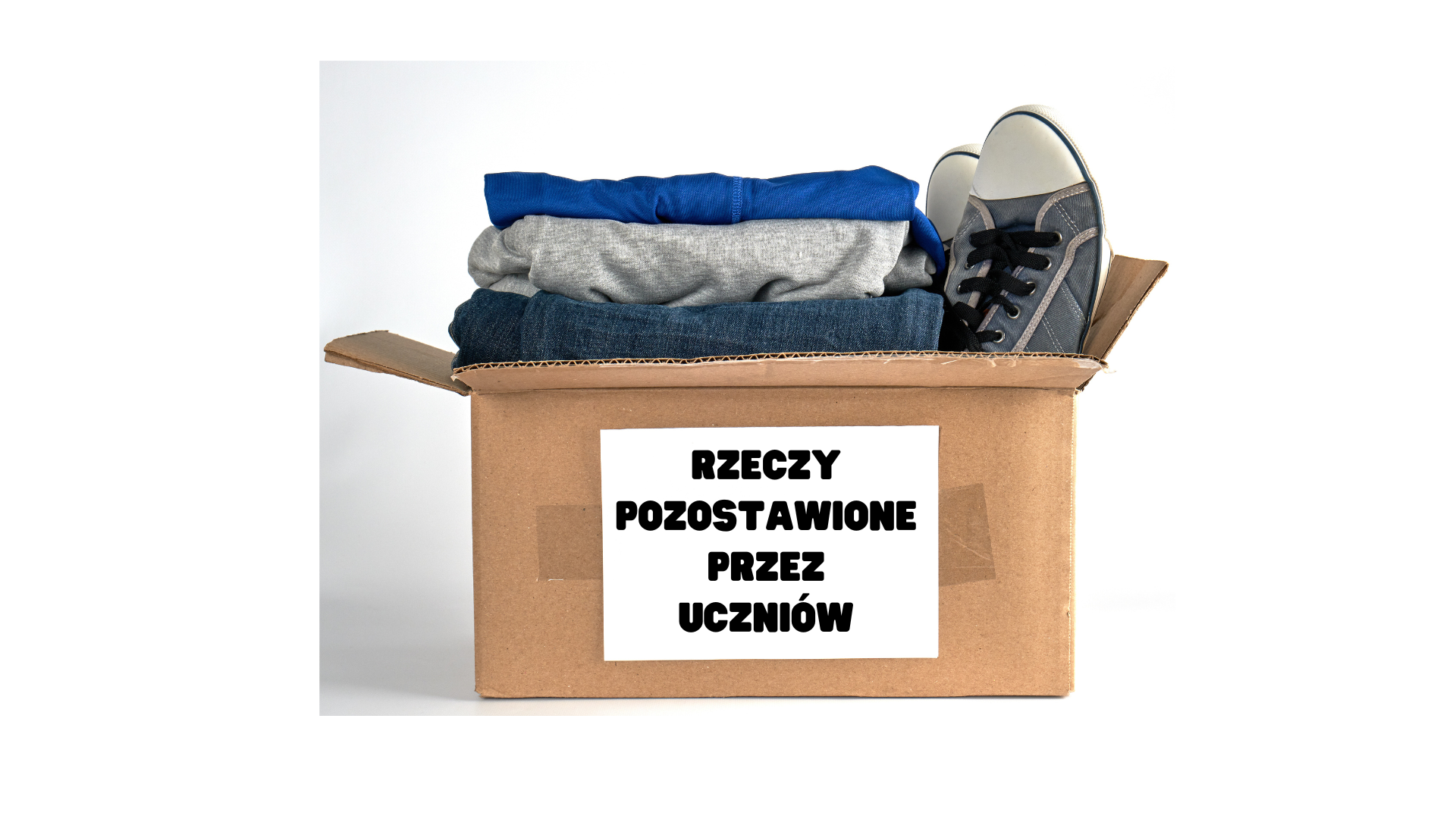 Ubrania i buty w kartonowym pudełku. Na pudełku napis: rzeczy pozostawione przez uczniów.