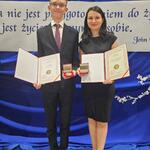Uczeń i nauczyciel pozują do zdjęcia Prezentują medale i dyplomy.