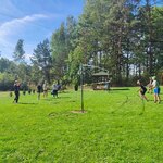 Uczniowie grają w siatkówkę na trawie