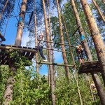 Uczniowie pokonują trasę w parku linowym. Są ubrani w kaski i uprzęże do wspinaczki