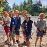 Uczniowie pozują do zdjęcia. Są ubrani w kaski i uprzęże do wspinaczki