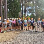 Uczniowie pozują do zdjęcia. Są ubrani w kaski i uprzęże do wspinaczki