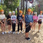 Uczniowie pozują do zdjęcia. Są ubrani w kaski i uprzęże do wspinaczki