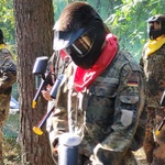 uczniowie w ubraniach maskujących i maskach idą do lasu