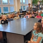 Dzieci w bibliotece słuchają czytanej książki