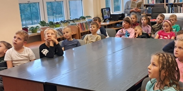 Dzieci w bibliotece słuchają czytanej książki