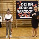 Pani Dyrektor przemawia podczas akademii. Po lewej stronie stoją uczniowie ubrani na galowo.