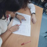 Uczennica z mamą siedzą przy ławce. Wspólnie sprawdzają treść dyktanda