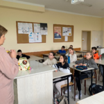 Uczniowie uczestniczą w zajęciach. Siedzą w ławkach.