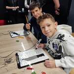 Uczniowie wykonują modele długopisem 3D. Siedzą przy stołach