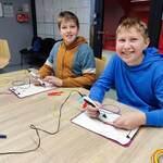 Uczniowie wykonują modele długopisem 3D. Siedzą przy stołach