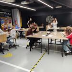 Uczniowie wykonują modele długopisem 3D. Siedzą przy stołach