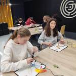 Uczennice wykonują modele długopisem 3D. Siedzą przy stołach