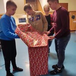 Uczniowie pakują prezent w papier ozdobny