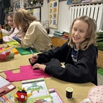 Uczniowie siedzą w ławkach. Wykonują prace z kolorowego filcu