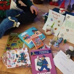 chłopiec siedzi na podłodze. Obok niego leżą upominki od klasy