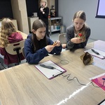 Uczniowie siedzą przy stolikach. Słuchają wykładu na temat druku 3D