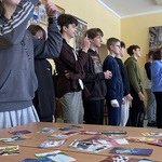 Uczniowie stoją obok sienie. Grają w grę. Pokazują emocje.