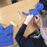 uczeń związuje bibułę na kształt sukienki
