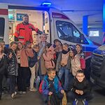 Klasa 2c pozuje do wspólnego zdjęcia z ratownikiem przed karetką