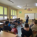 Uczniowie siedzą w okręgu. Biorą udział w zajęciach.