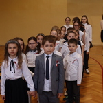 Uczniowie tańczą poloneza na sali gimnastycznej podczas uroczystej akademii