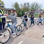 Uczniowie na rowerach odpowiadają na pytania policji.