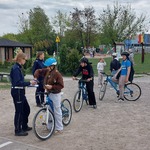 Uczniowie na rowerach odpowiadają na pytania policji.
